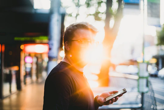 A person using an Android app outdoors, with sunlight highlighting the screen.
