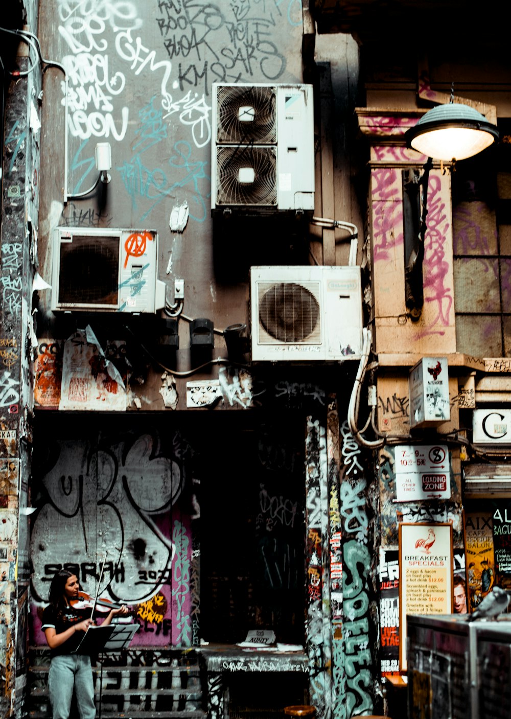 femme jouant du violon devant un bâtiment avec des murs de graffitis