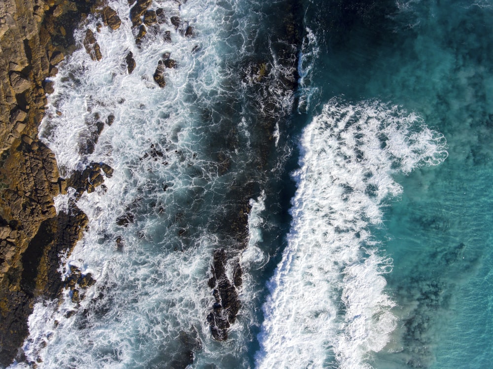 Vista a volo d'uccello delle onde d'acqua impetuose contro la roccia