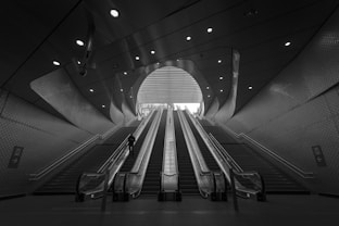 grayscale photography of person on escalator