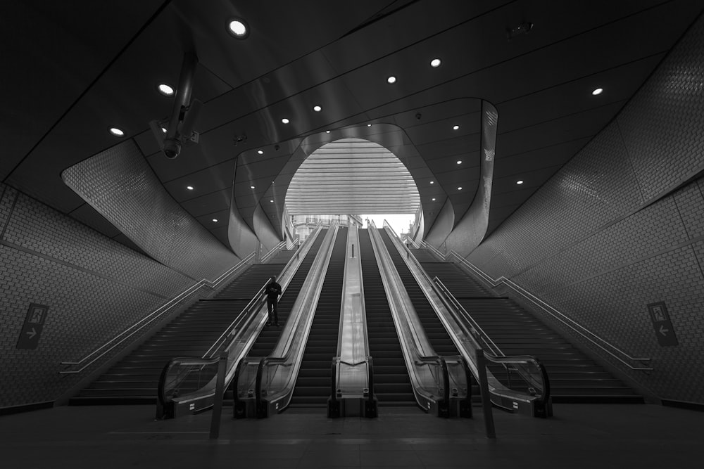 grayscale photography of person on escalator