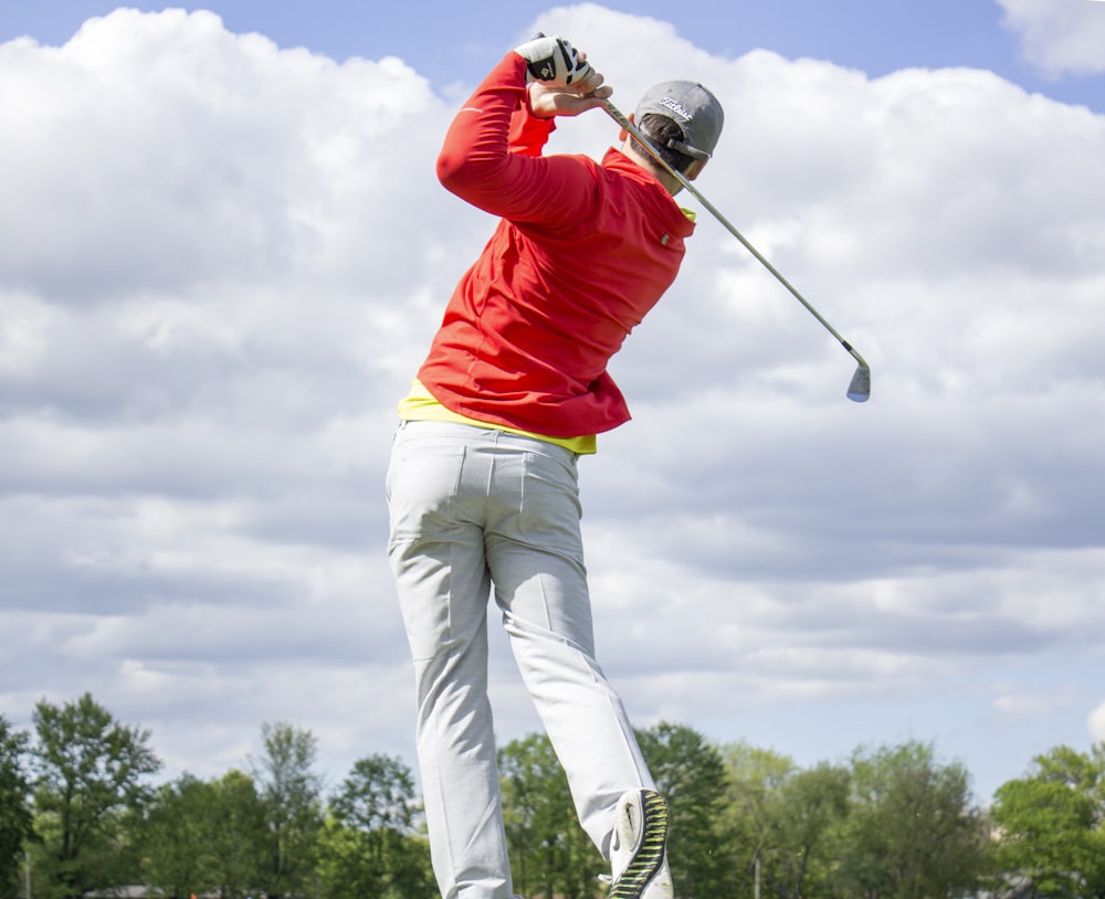 Homem no golfe de manga comprida vermelha