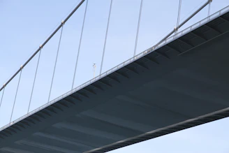 A detailed close-up of a modern European bridge under construction, showing steel cables and workers.