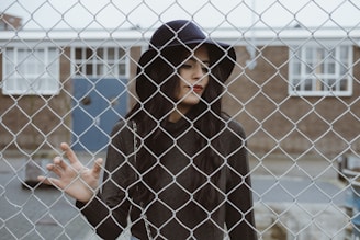 woman touching cyclone fence