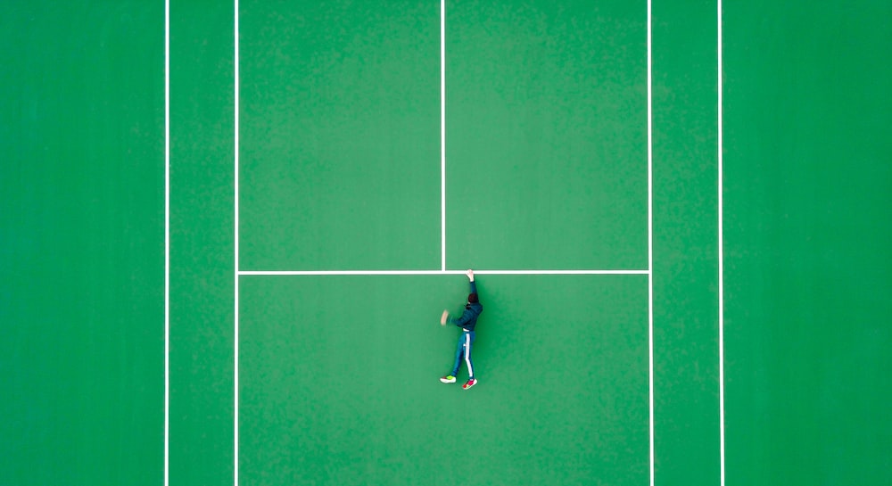 aerial photography of person lying on tennis court