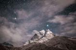 A serene night sky over a mountain range, dotted with countless stars.