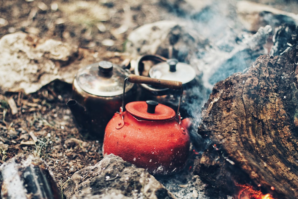 three red and gray kettles on charcoals