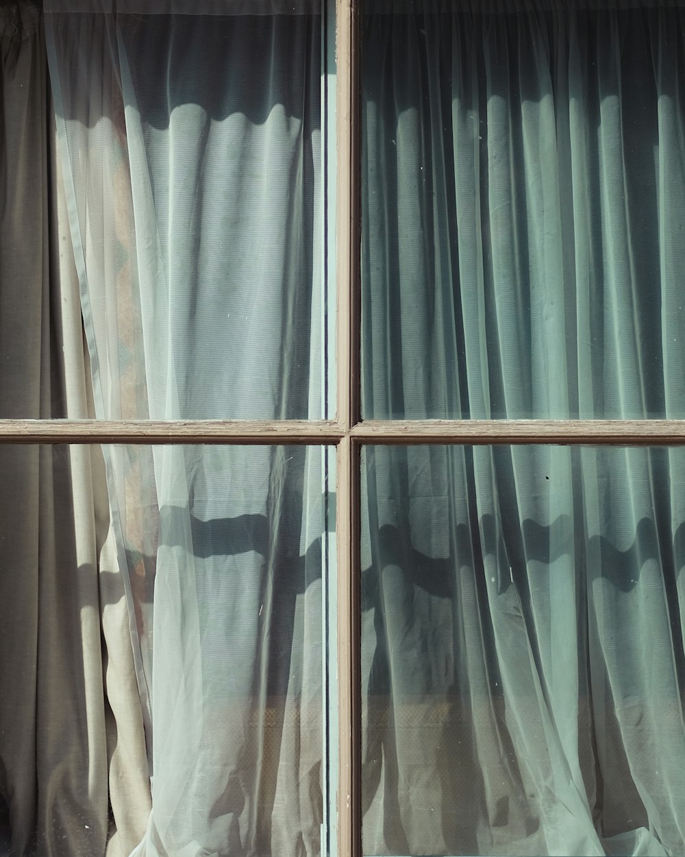 Glasfenster mit blaugrünem und weißem Vorhang