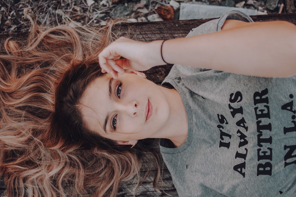 mujer vestida con camiseta gris tirada en el suelo