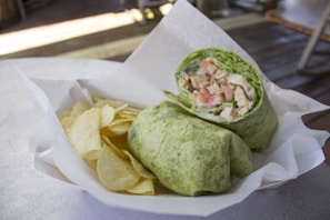 A vibrant combo meal featuring a spicy chicken wrap with colorful veggies and a cold drink