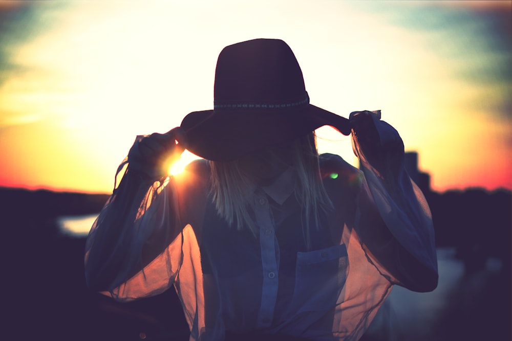 silhouette of woman holding her hat