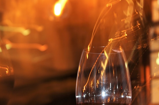 A softly blurred close-up of a wine glass catching the light, hinting at warmth and anticipation.
