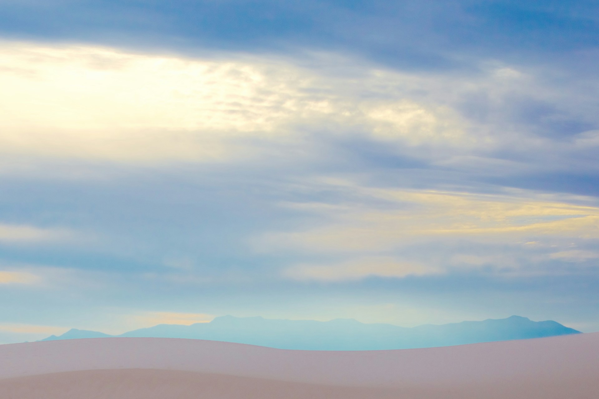 A serene early morning landscape with soft sand dunes under a gentle sky mist blue dawn, evoking calm and openness.