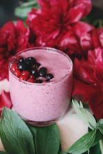 A vibrant pink smoothie topped with fresh berries and a straw.