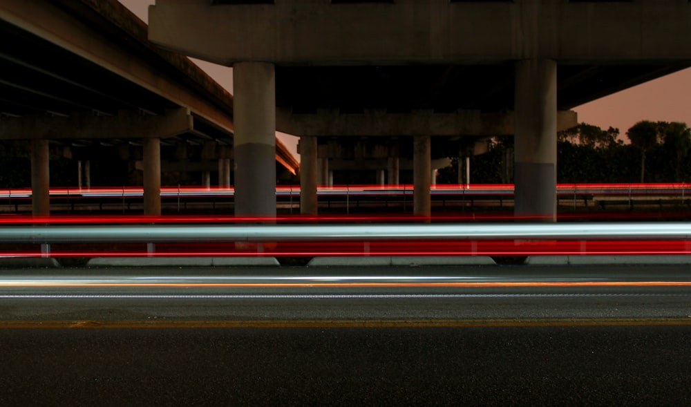 timelapse photography of vehicle light crossing on road under concrete dock