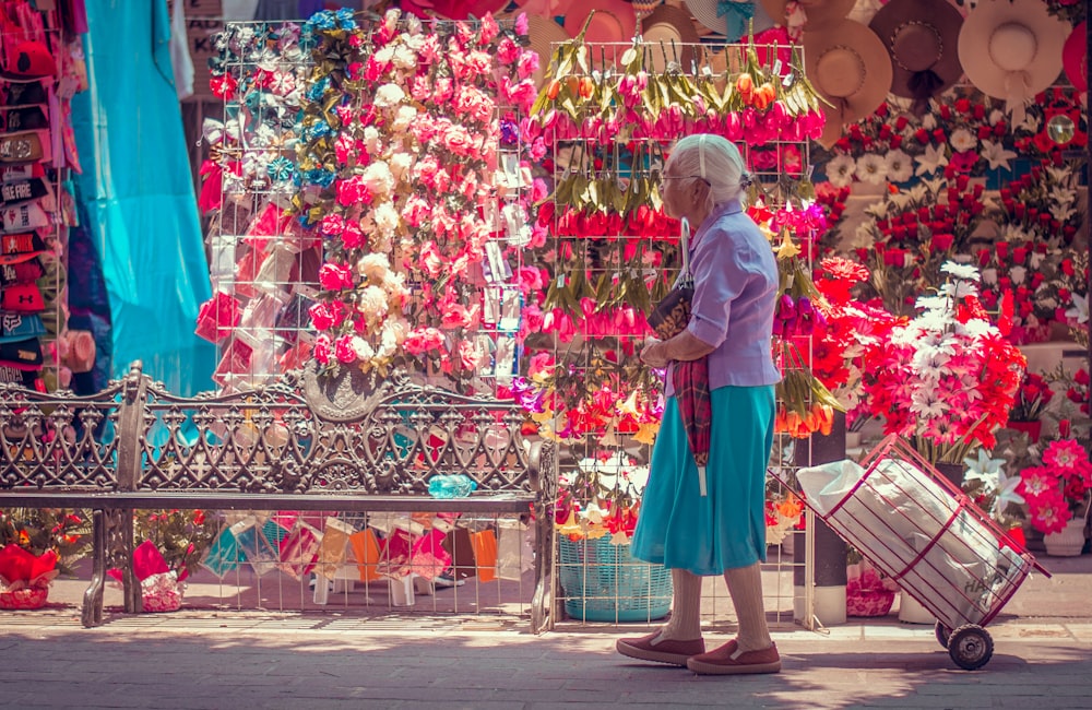 woman in pink long sleeve shirt and blue skirt standing on street with red and white