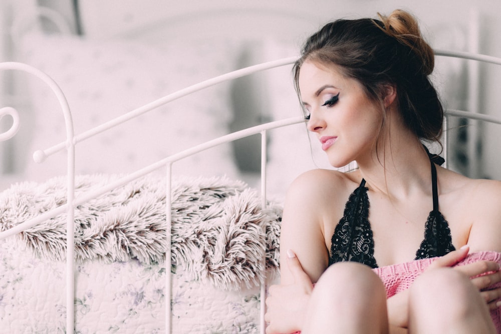 woman wearing black lingerie holding pink pillow