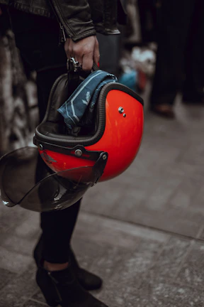 Close-up of rugged hands holding a vintage motorcycle helmet with a rebellious sticker.