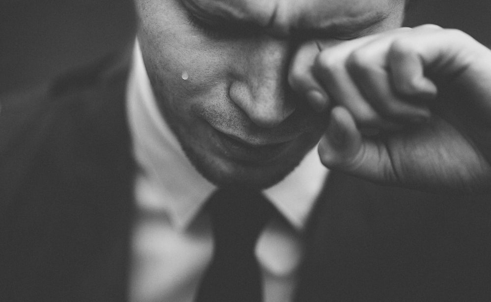 A black-and-white shot of a crying man in a suit and tie