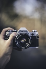 person holding black Canon DSLR camera