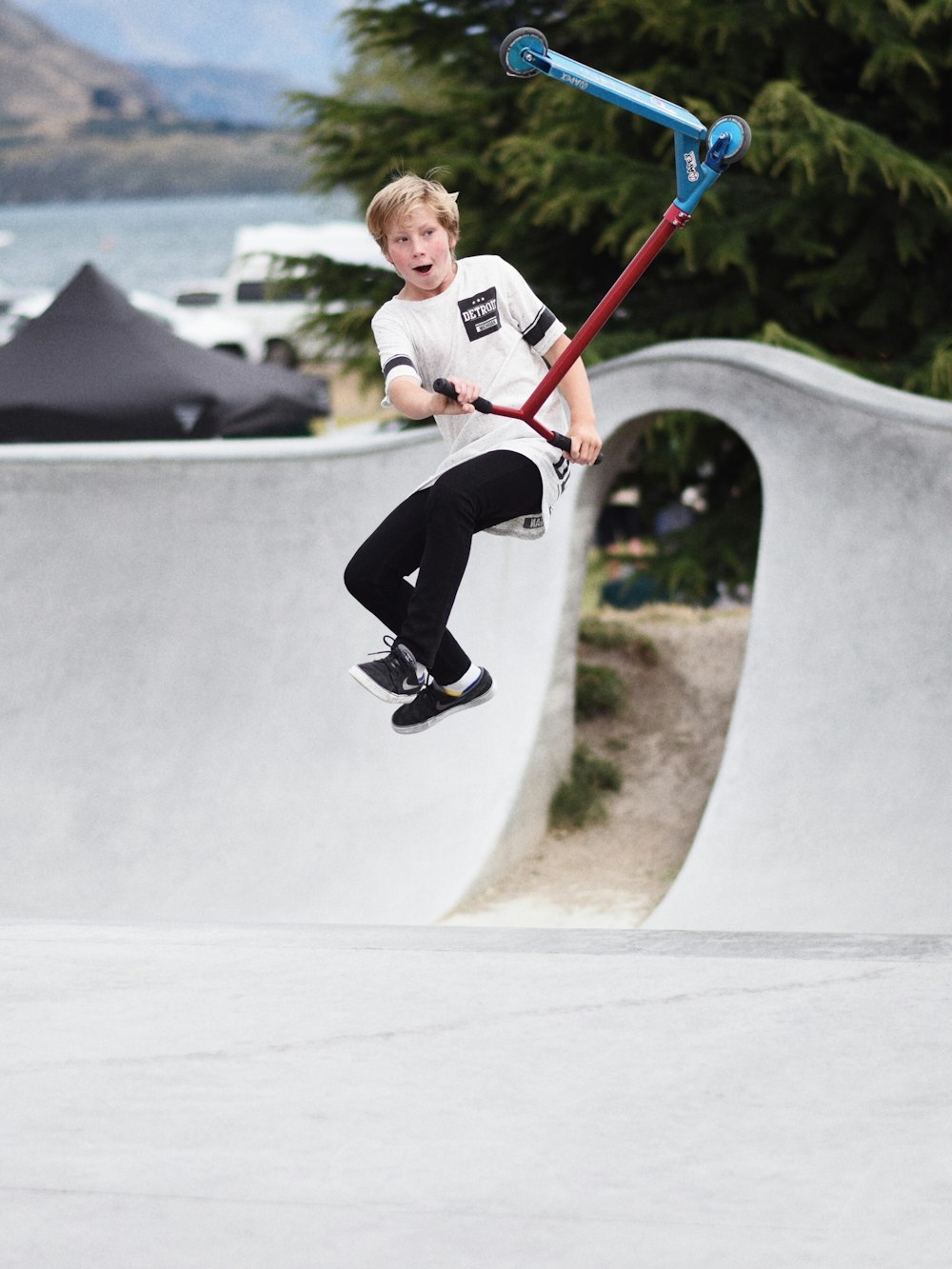 boy jumping off from red scooter