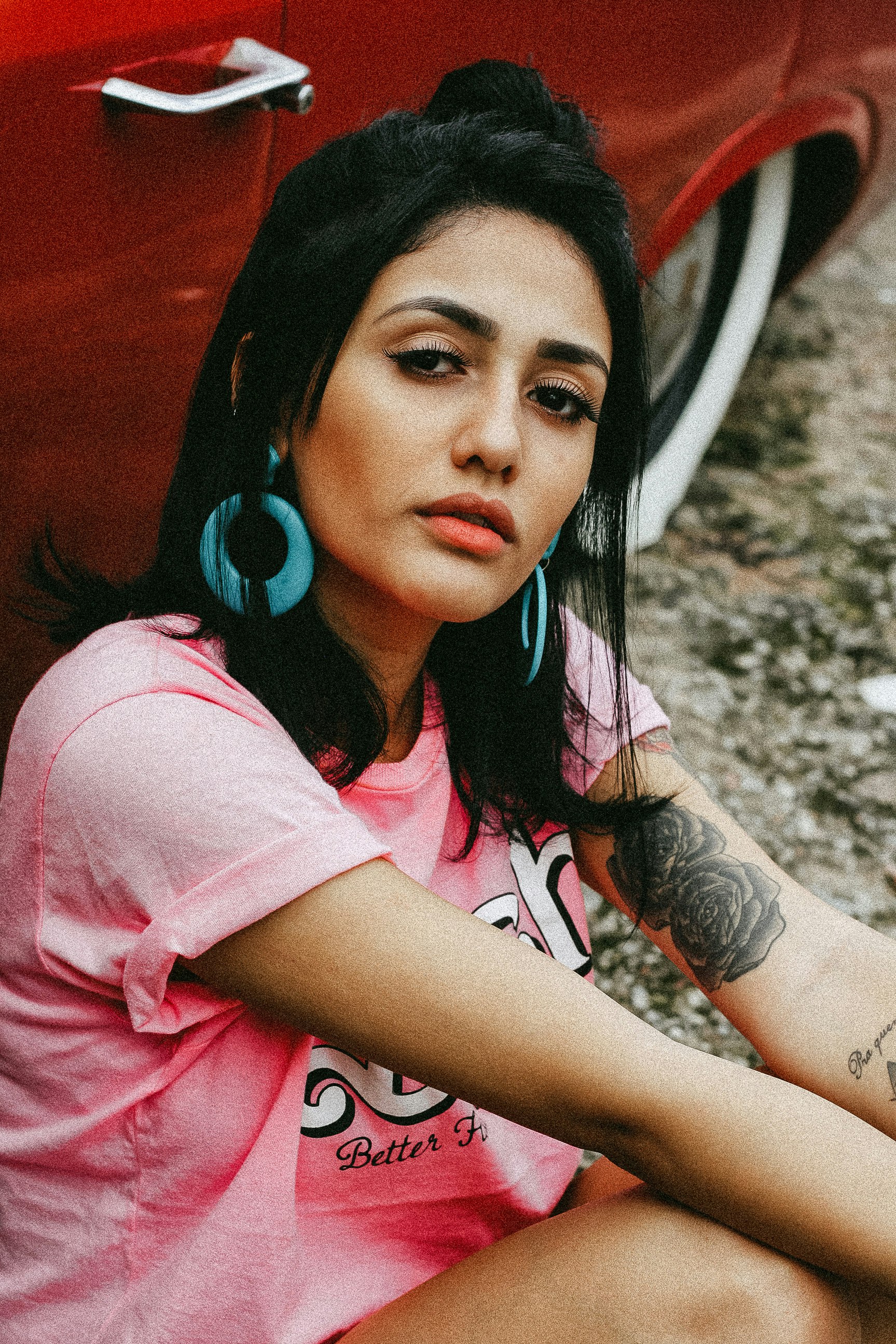 woman sitting beside red car