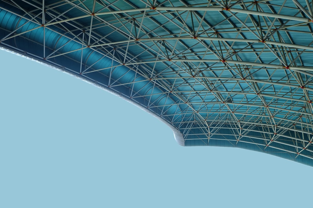 an airplane flying in the air under a blue roof