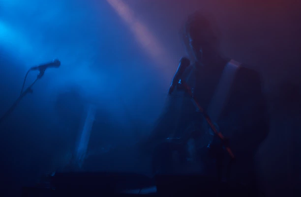 Warm studio scene with a musician playing guitar surrounded by soft blue and red lighting.