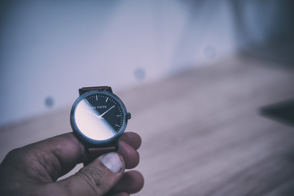 person holding analog watch displaying 10:10