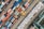 An aerial view of a busy shipping port filled with numerous colorful shipping containers. The scene includes various sizes and colors of containers arranged in neat rows, with cranes and vehicles for transportation. The layout is orderly and structured, indicating a highly organized operation.