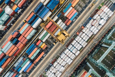 An aerial view of containers stacked neatly at a busy international port.