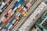 An aerial view of a busy shipping port filled with numerous colorful shipping containers. The scene includes various sizes and colors of containers arranged in neat rows, with cranes and vehicles for transportation. The layout is orderly and structured, indicating a highly organized operation.