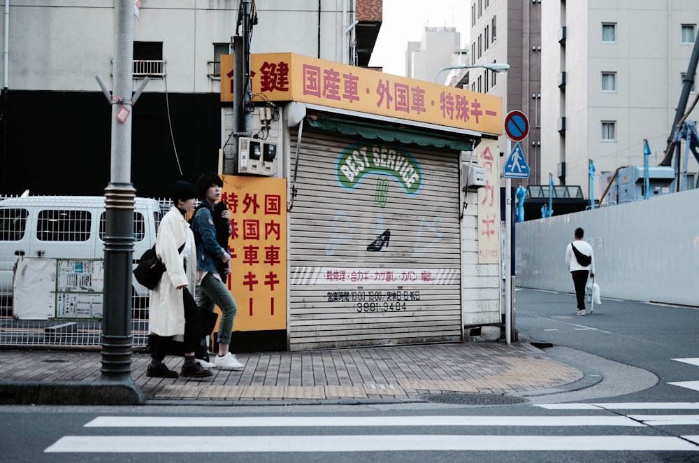 two women walking near street post and pedestrian lane