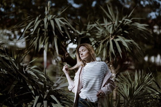 woman holding her hair closing eyes ner trees in Batumi Georgia