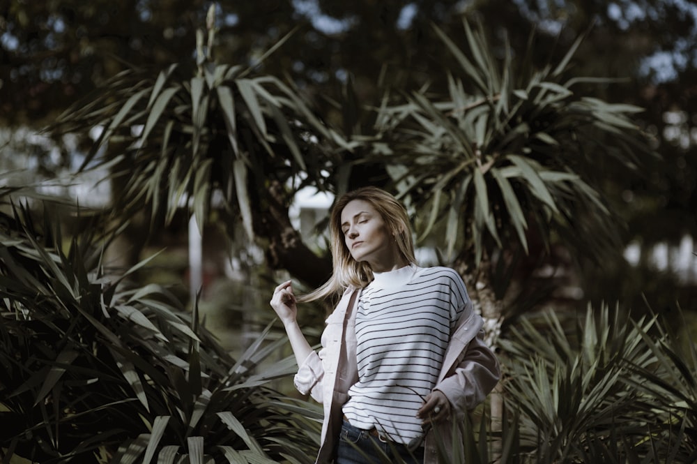 woman holding her hair closing eyes ner trees