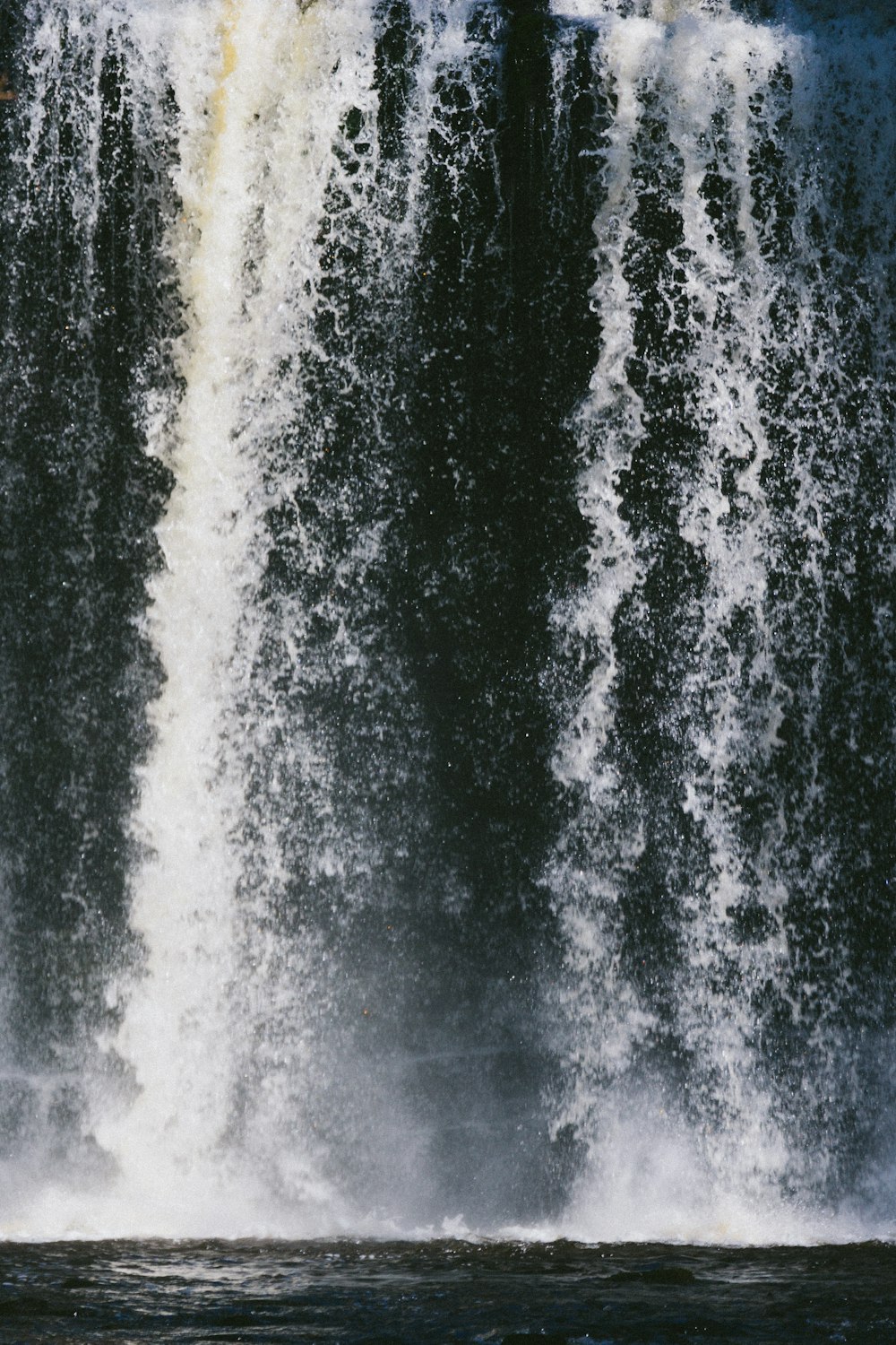 a man riding a surfboard in front of a large waterfall