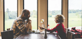 A warm scene of a parent and child engaged in a calm, focused conversation at a sunlit table.