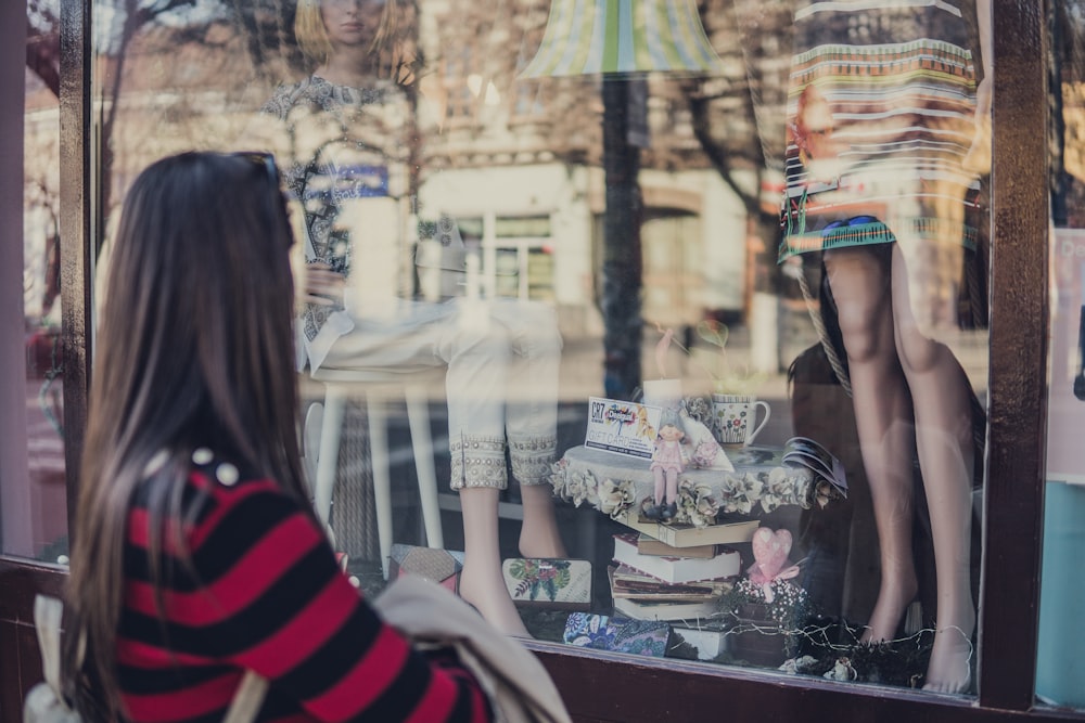 femme debout près du magasin tout en regardant le mannequin