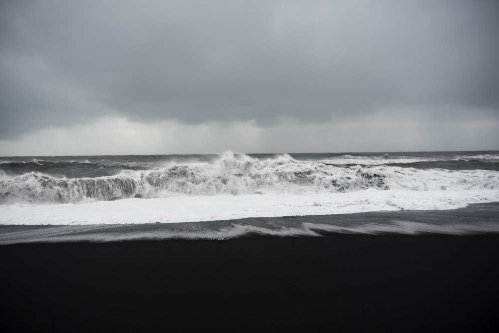 grayscale photo of shore under clouds