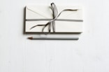 white envelop and gray pencil on white panel