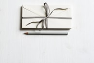 white envelop and gray pencil on white panel