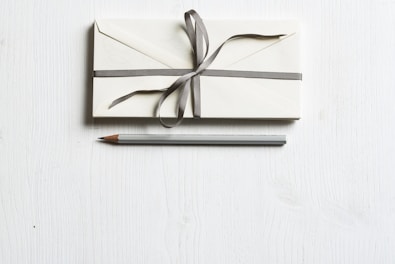 white envelop and gray pencil on white panel