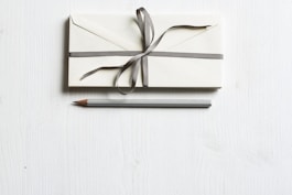 white envelop and gray pencil on white panel