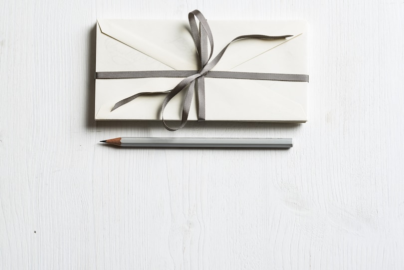 white envelop and gray pencil on white panel