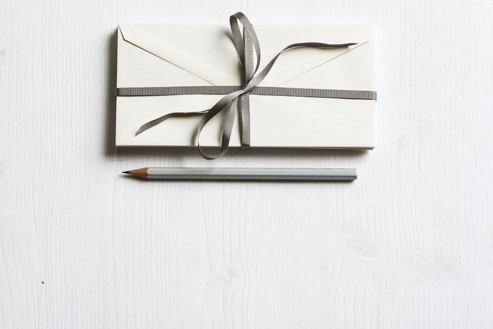 weißer Umschlag und grauer Bleistift auf weißem Panel