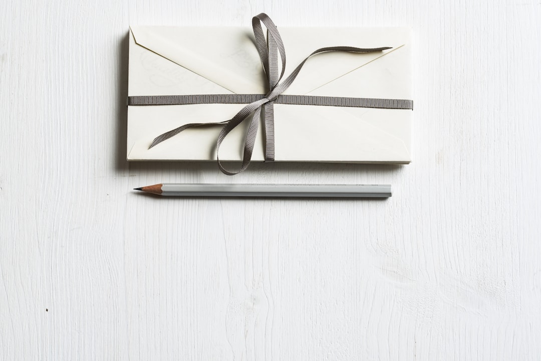 white envelop and gray pencil on white panel,