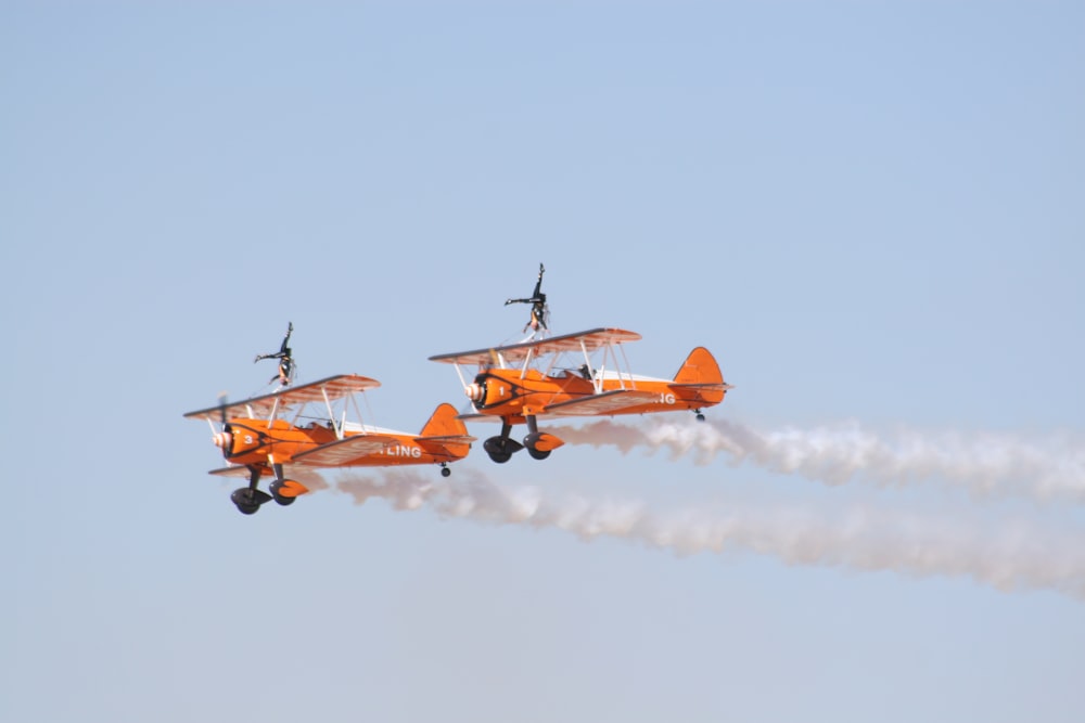 photo of two orange flying biplanes