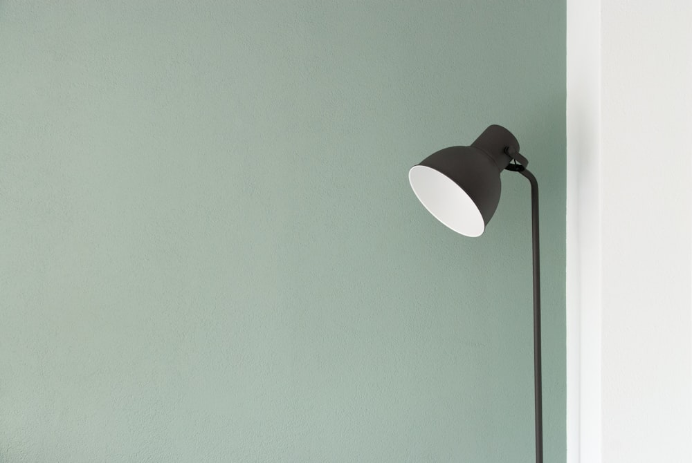 A floor lamp against a pastel green wall