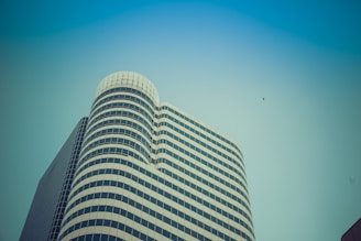 A high-rise building showcasing custom metal façades and structural glass under a clear blue sky.