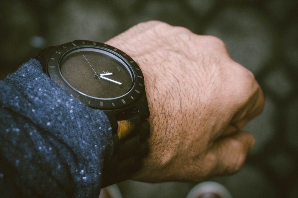 round black analog watch in left human wrist